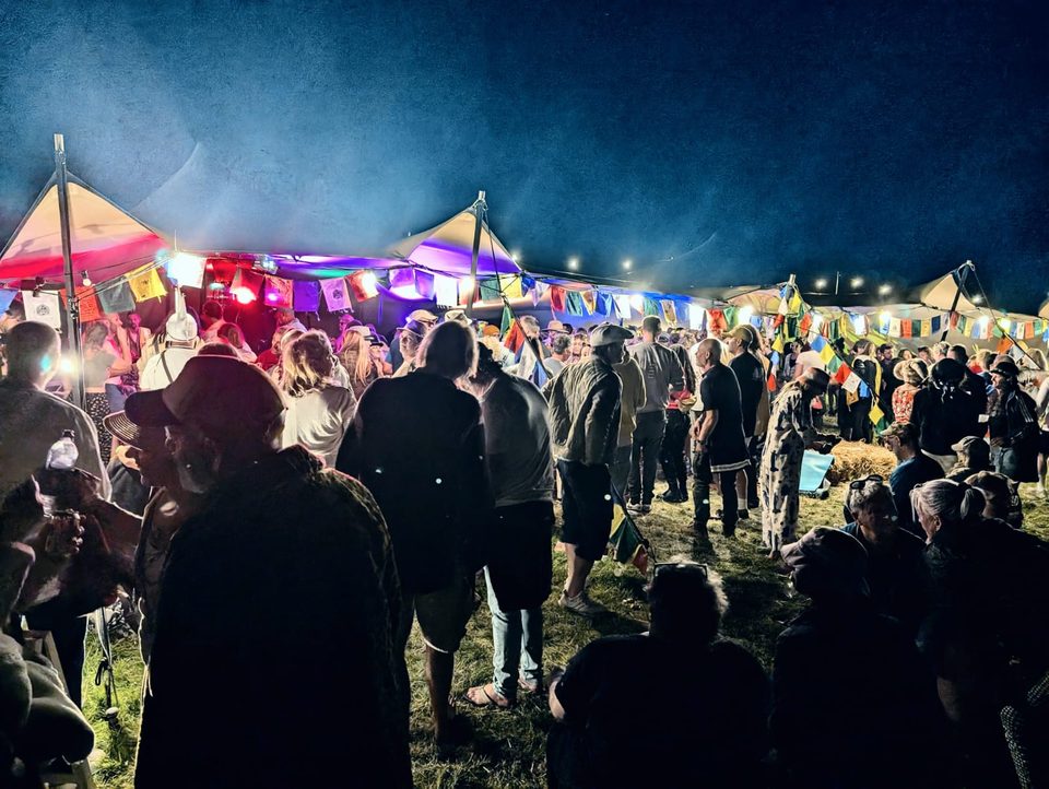 Night falls on the We Are Love festival field in 2024, lit tents and a crowd in silhouette